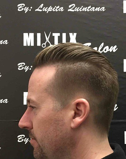 Men's side-part taper cut, in front of a backdrop reading By: Lupita Quintana